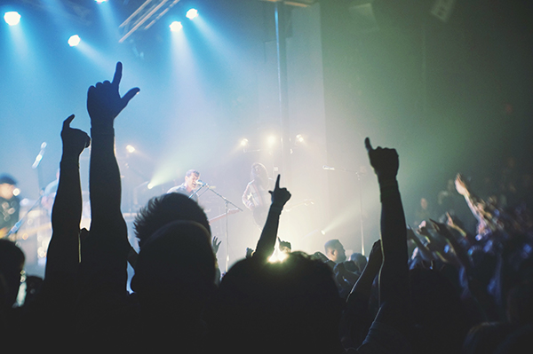 Image of crowd with hands raised watching a band perform